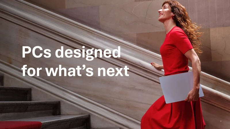 A person in a red dress walks up a marble staircase holding a laptop, with text reading 'PCs designed for what’s next.'