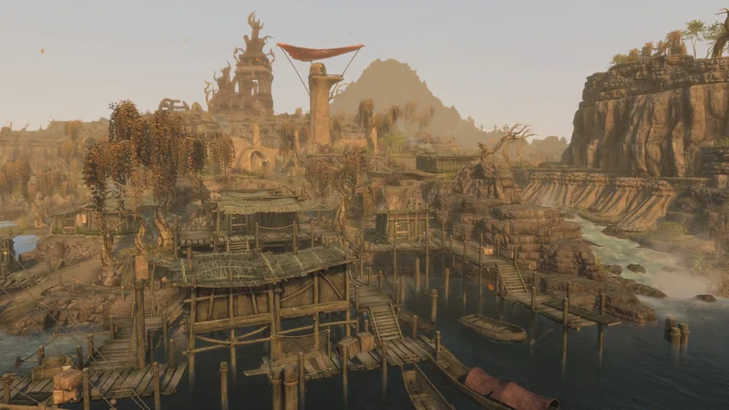 A scenic landscape from a fantasy game depicts a rustic village with woven huts, wooden walkways over water, and a towering ancient structure in the background against a mountainous backdrop.