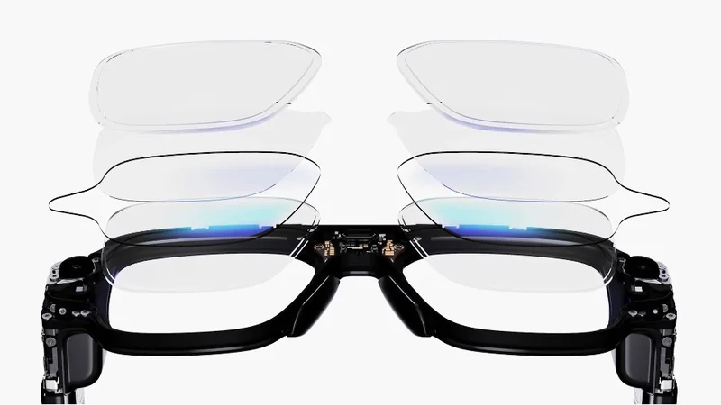 Black rectangular smart glasses with exposed electronics, shown front-on with multiple transparent lens layers floating above each frame, suggesting interchangeable or adjustable lenses on a white background