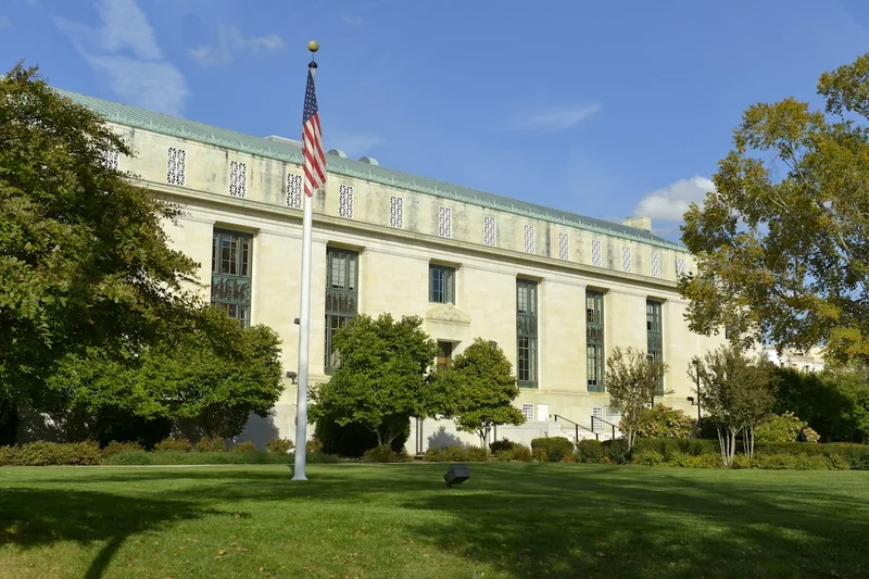 Image of a lawn and a square marble Greek-revival style building.