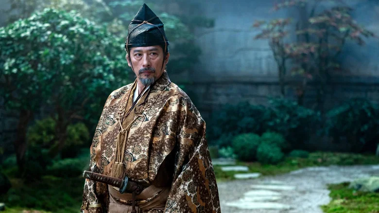 Shogun's Yoshii Toranga stands in a traditional golden robe and black headdress, his sword at the ready.