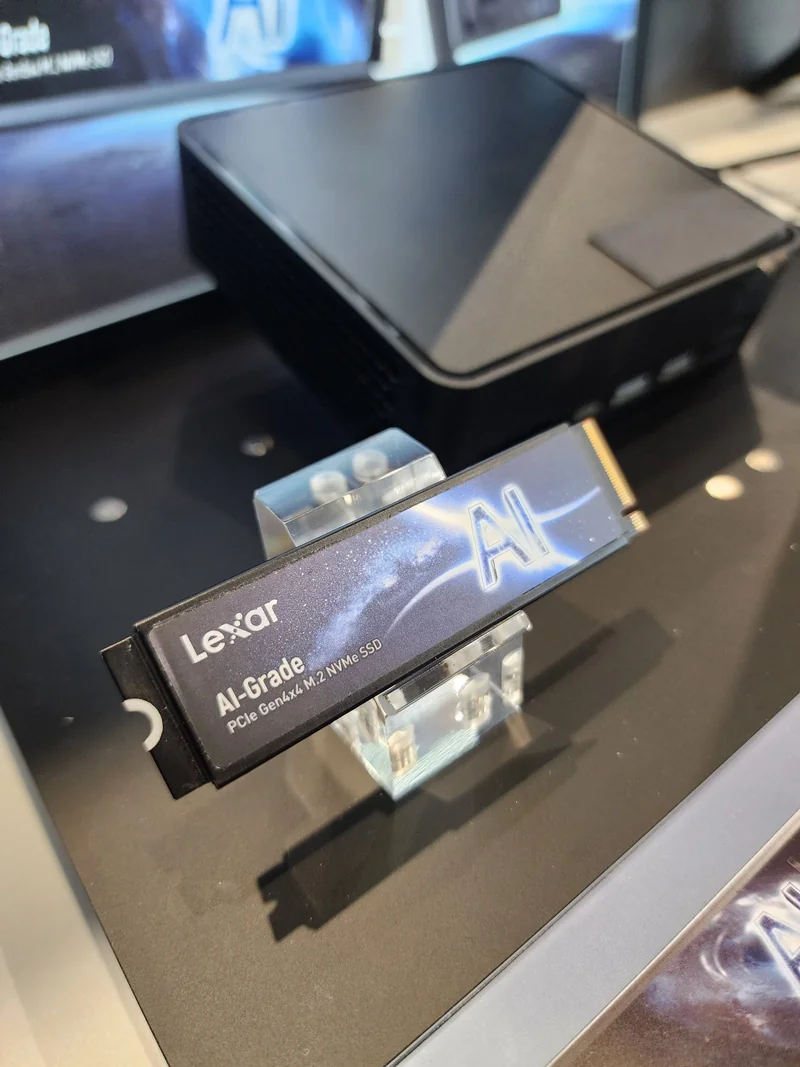 A Lexar PCIe Gen4x4 M.2 NVMe SSD labeled 'AI-Grade' is displayed on a stand next to a black compact PC case.