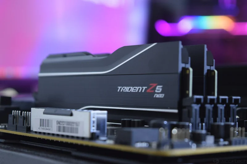 G.Skill Trident Z5 Neo RAM modules are installed on a motherboard with a blurred RGB-lit background.