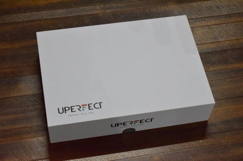 A white box with the UPERFECT logo and the slogan Perfect Your Life on a wooden surface.