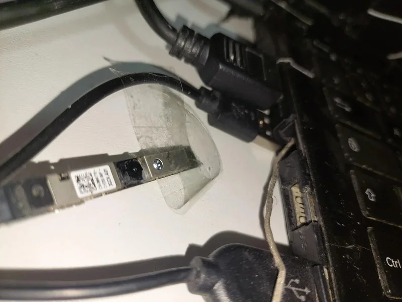The image shows a disassembled laptop webcam module taped near an unbranded keyboard and connected cables.