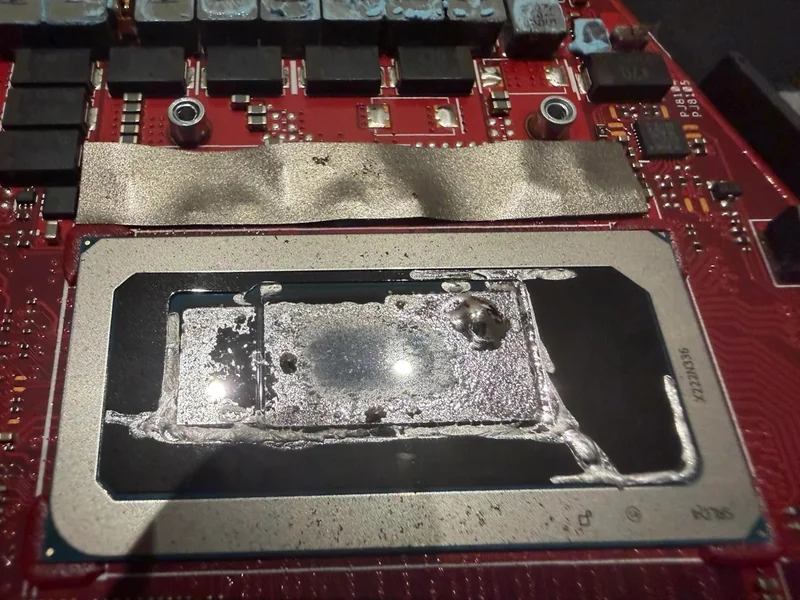 A close-up of an unbranded chip on a red circuit board showing thermal paste residue.