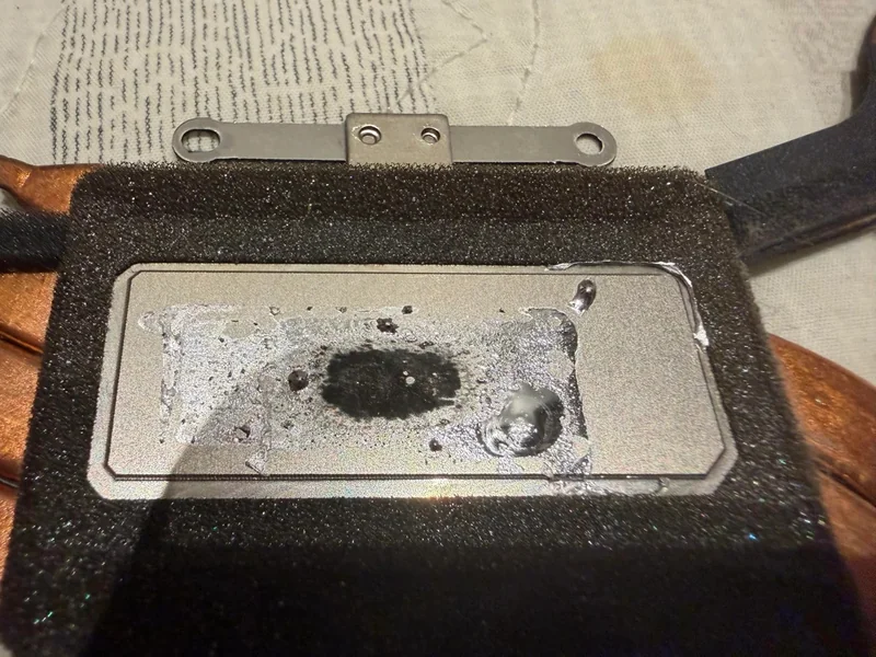 A close-up of a GPU with thermal paste residue and a mounting bracket attached.