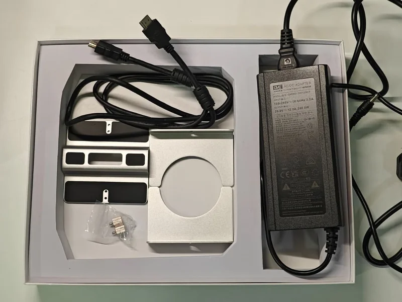 A content overview image of a wall mount kit and a MEAN WELL model GSM220B20-R7B AC/DC adapter.