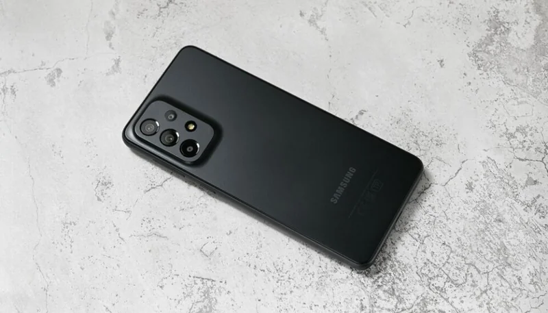 Black Samsung Galaxy A33 (2022) smartphone lying diagonally on a light gray textured surface
