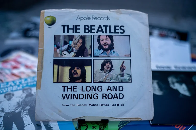 An original Apple Records single sleeve of "The Long and Winding Road," photographed among other Beatles records.