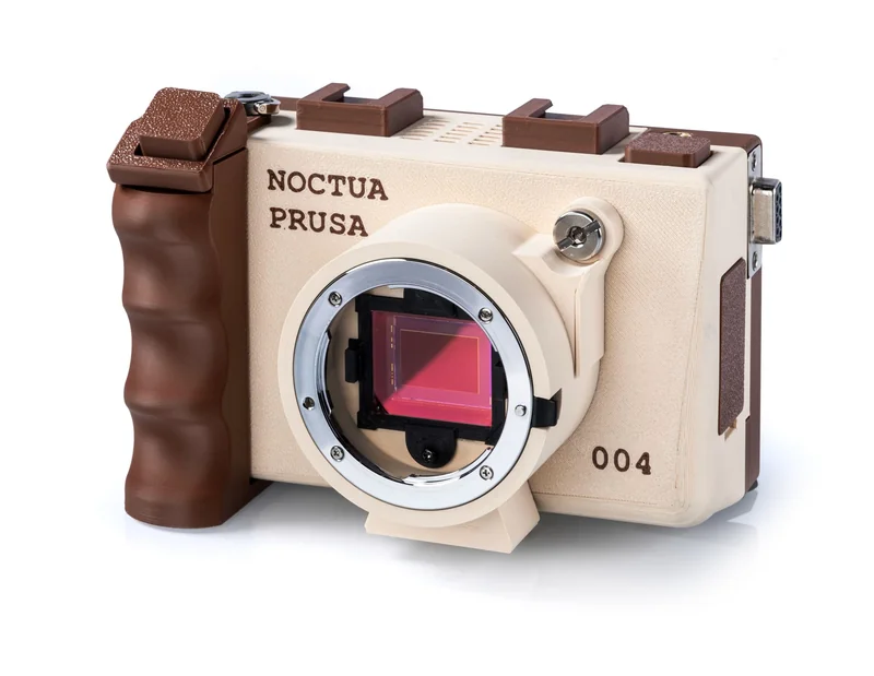 A Noctua Prusa camera with 004 marked on the side, featuring a visible digital image sensor and a brown grip design.