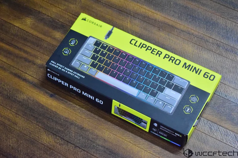 A Corsair Clipper Pro Mini 60 Hall Effect gaming keyboard box with a colorful backlit keyboard image on a wooden surface.