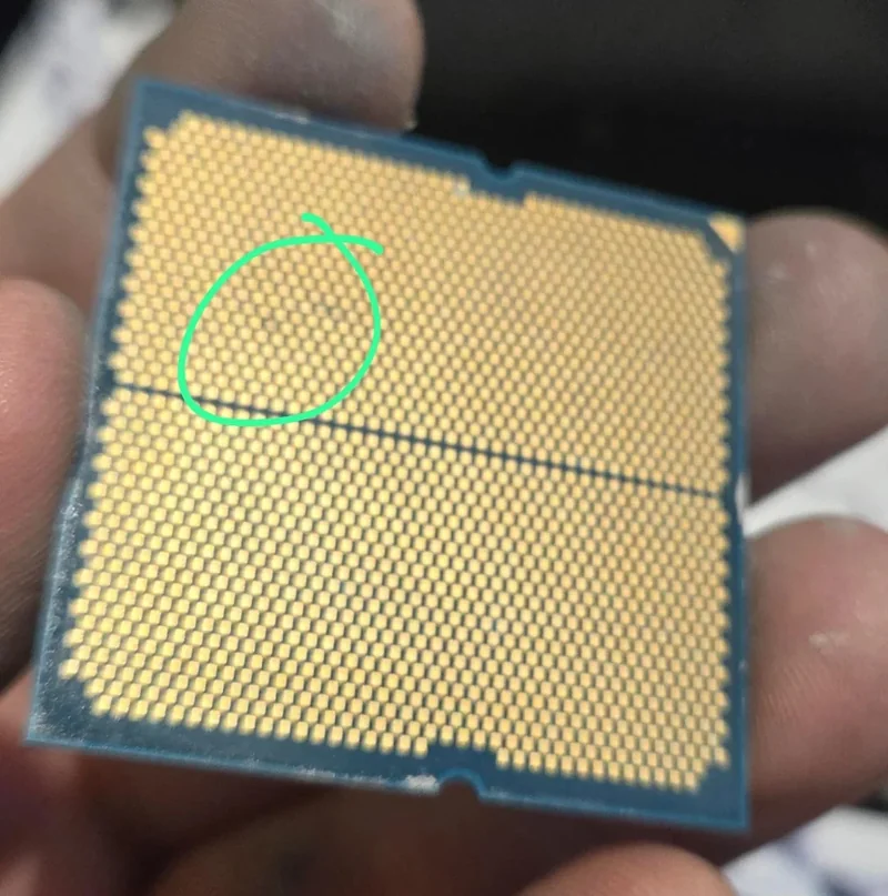 A close-up view of the underside of an Intel CPU, with a circled area highlighting a defect or anomaly in the pin grid.