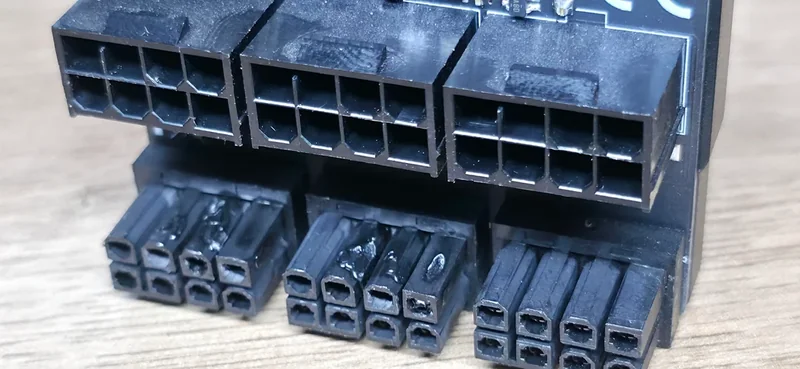 A close-up of a black PCIe power connector with visible signs of melting on the lower pins.