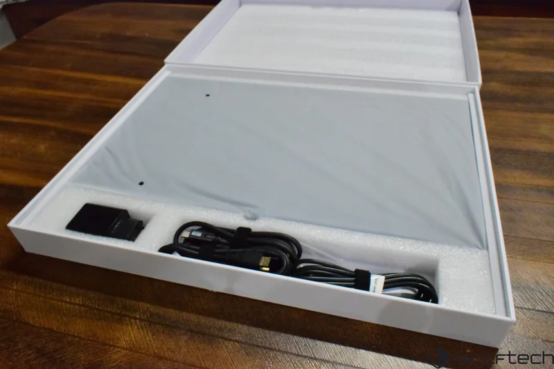 An unbranded monitor in packaging with power adapter and cables, including an HDMI cable.