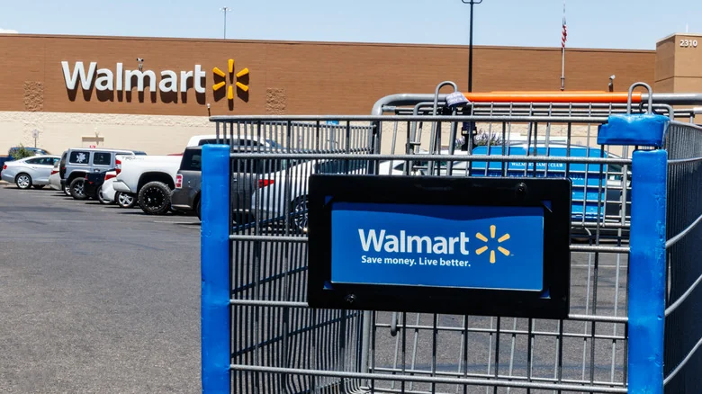 A Walmart shopping cart sits front and center in a crowded store parking lot.