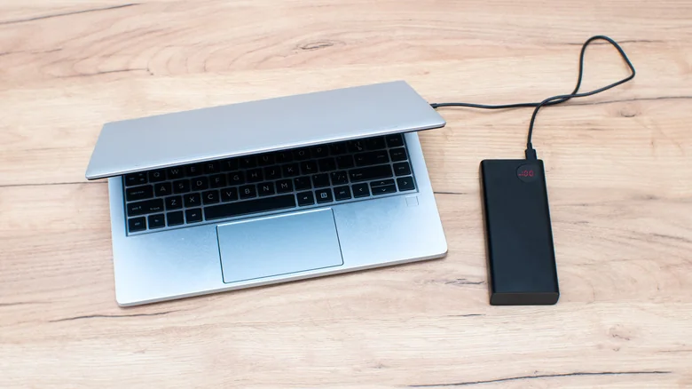Half-closed laptop charging from a connected portable power bank.