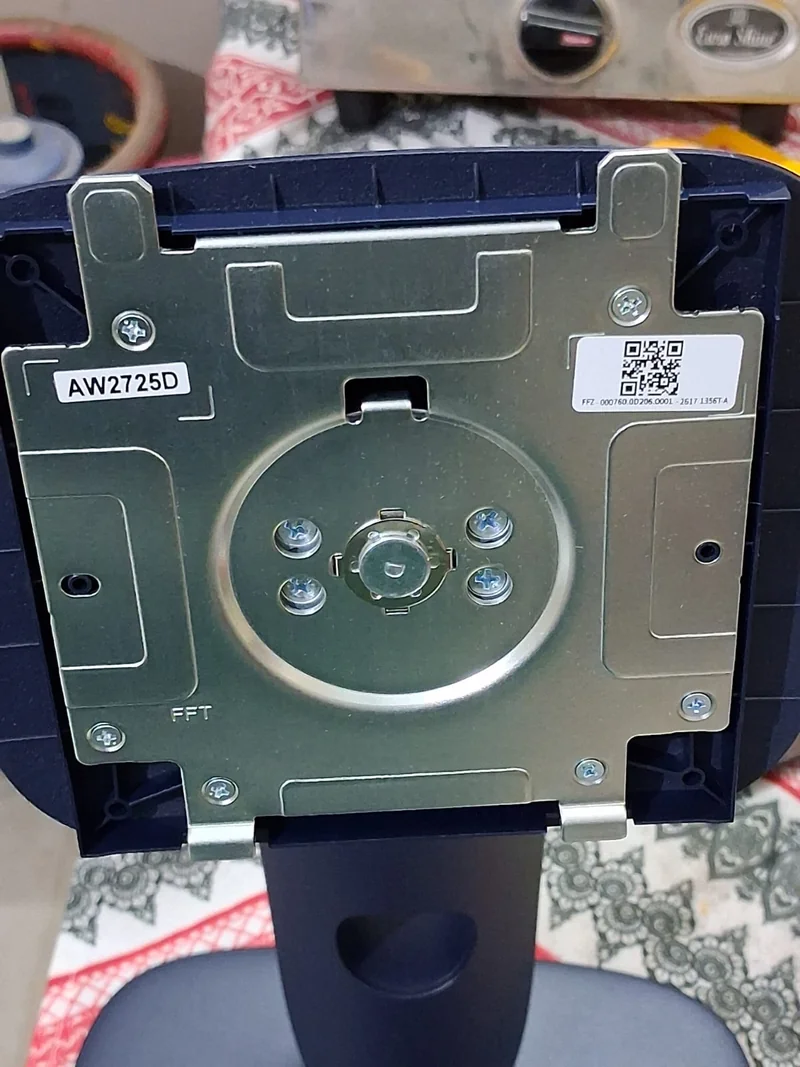 A close-up of the back of a monitor stand labeled 'AW2725D,' with visible mounting mechanism and screws.