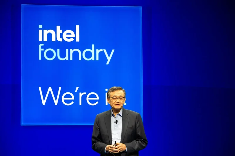 An executive stands in front of a blue screen displaying 'intel foundry We're in.'