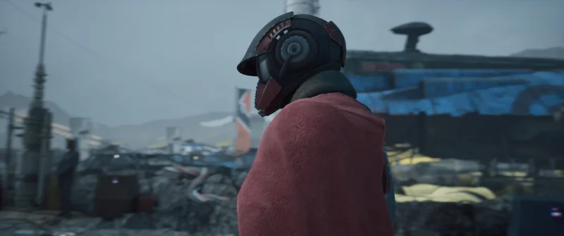 A character wearing a helmet and a red cloak stands in a dystopian outdoor setting with industrial structures in the background.