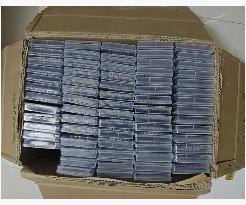 A large cardboard box containing neatly stacked transparent plastic cases filled with electronic components.
