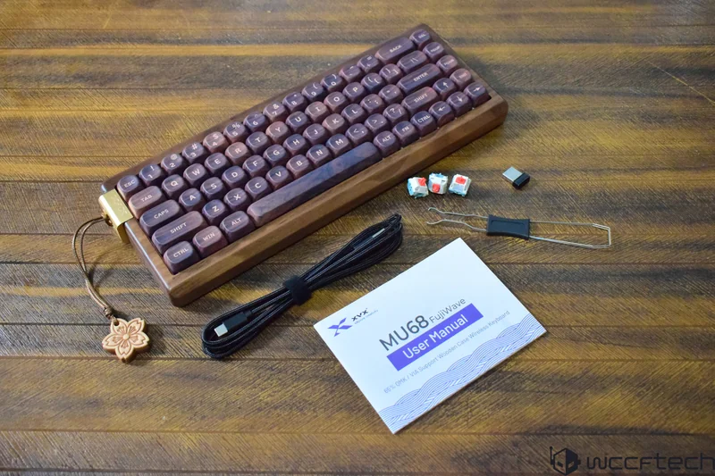 A wooden-cased XVX MU68 FujiWave wireless keyboard is displayed with key switches, a USB cable, and a 'User Manual' on a wooden surface.